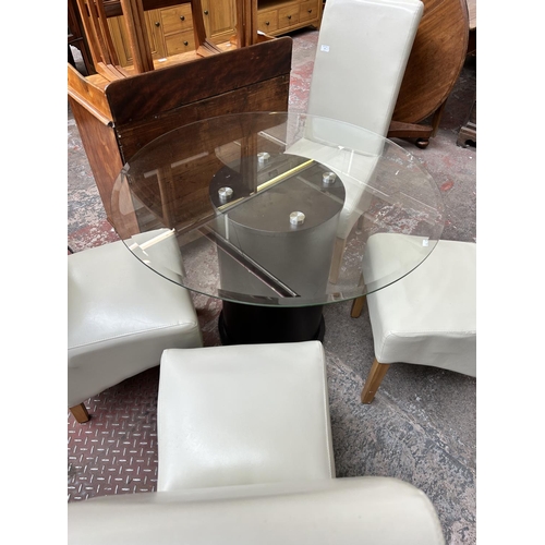 53 - A modern glass top circular dining table on brown leatherette pedestal base and four cream leatheret... 