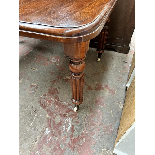 60 - A Victorian mahogany rectangular wind out extending dining table with reeded supports and winder - a... 