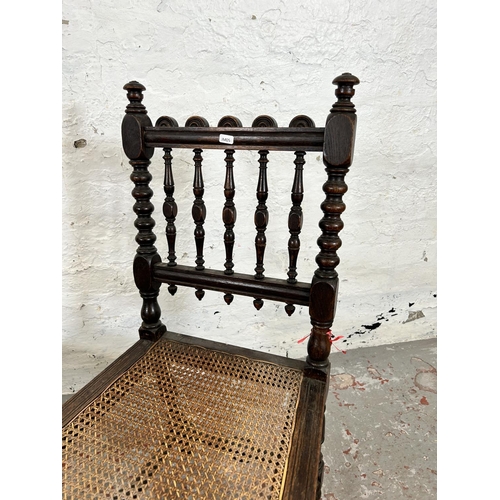 78 - A pair of Victorian carved oak and rattan occasional chairs, both monogrammed 'JHEH' to underside