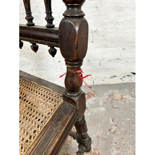 78 - A pair of Victorian carved oak and rattan occasional chairs, both monogrammed 'JHEH' to underside