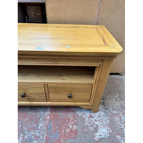 94 - A modern oak TV stand with three lower drawers - approx. 58cm high x 114cm wide x 44cm deep