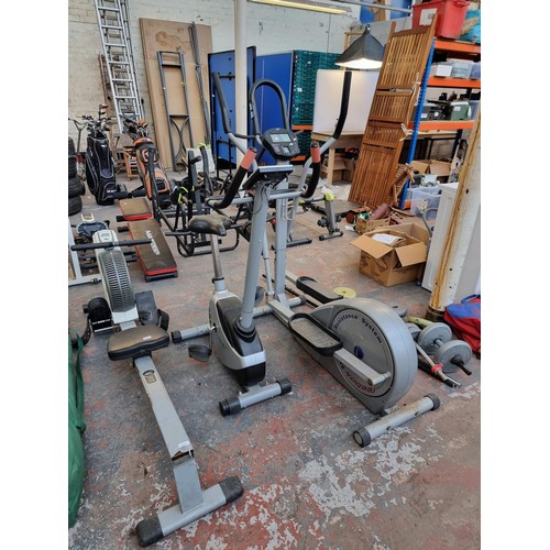 301 - A collection of exercise equipment to include V-Fit rowing machine, black metal barbell, Reebok cros... 