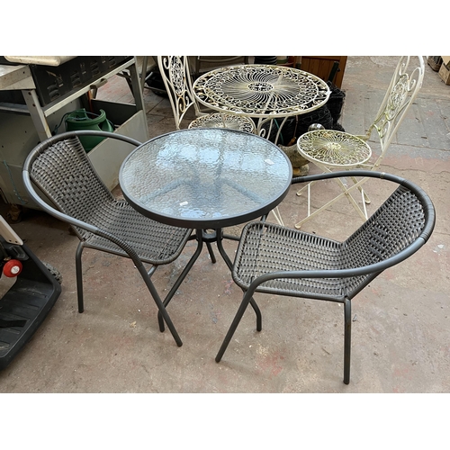 382A - A grey metal three piece patio set comprising circular table with tempered glass and two rattan effe... 