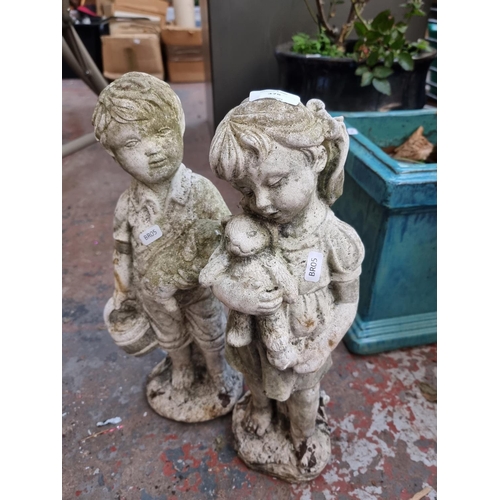 378 - A pair of cast stone boy and girl garden ornaments