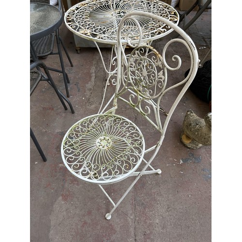 382 - A 19th century style filigree effect wrought iron three piece patio set comprising two folding chair... 