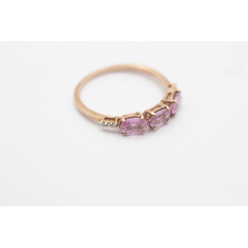 1036 - A 9ct gold pink sapphire three stone ring with diamond accents - approx. gross weight 1.7 grams