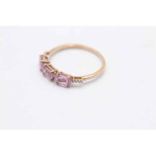 1036 - A 9ct gold pink sapphire three stone ring with diamond accents - approx. gross weight 1.7 grams