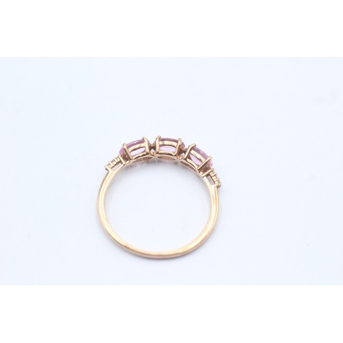 1036 - A 9ct gold pink sapphire three stone ring with diamond accents - approx. gross weight 1.7 grams