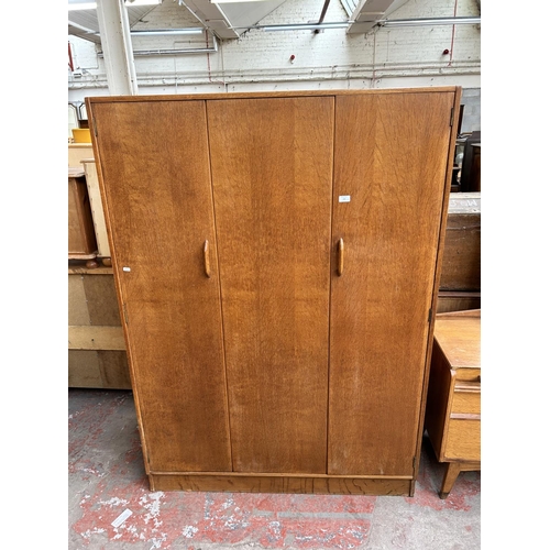 151 - A mid 20th century G Plan oak two piece bedroom suite comprising dressing table and triple wardrobe