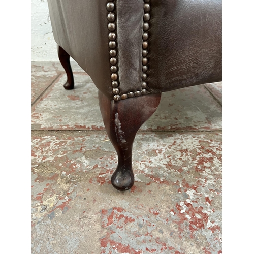 133 - A brown leather Chesterfield wing back armchair