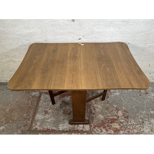 142 - A mid 20th century oak effect drop leaf gate leg dining table