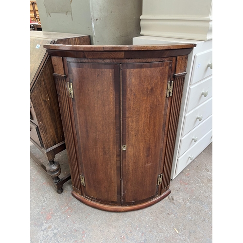 183 - A Georgian oak and mahogany crossbanded bow front wall mountable corner cabinet