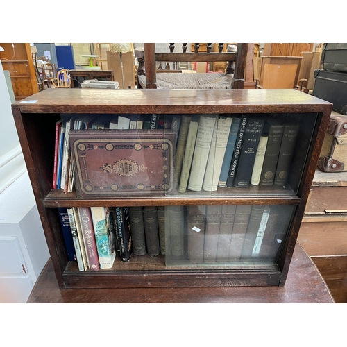 186 - A mid 20th century oak two tier bookcase with four glass sliding doors and books