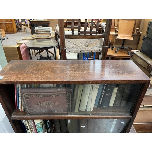 186 - A mid 20th century oak two tier bookcase with four glass sliding doors and books