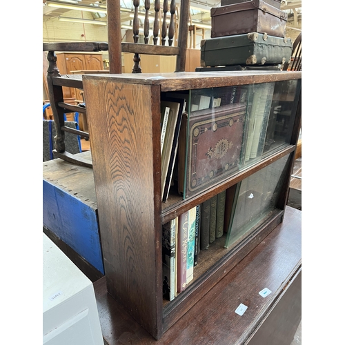 186 - A mid 20th century oak two tier bookcase with four glass sliding doors and books