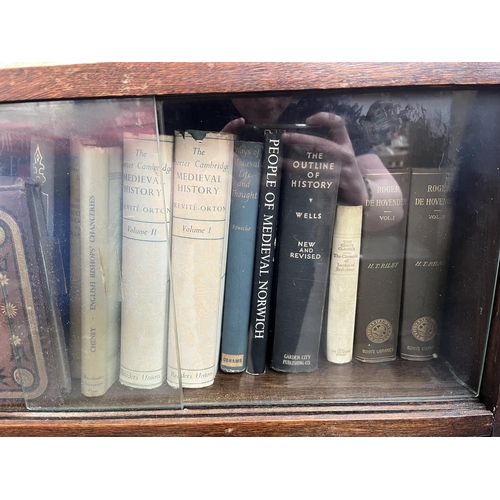 186 - A mid 20th century oak two tier bookcase with four glass sliding doors and books