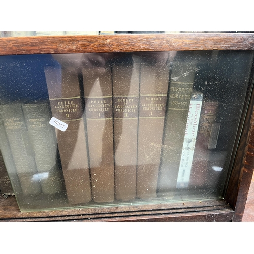 186 - A mid 20th century oak two tier bookcase with four glass sliding doors and books