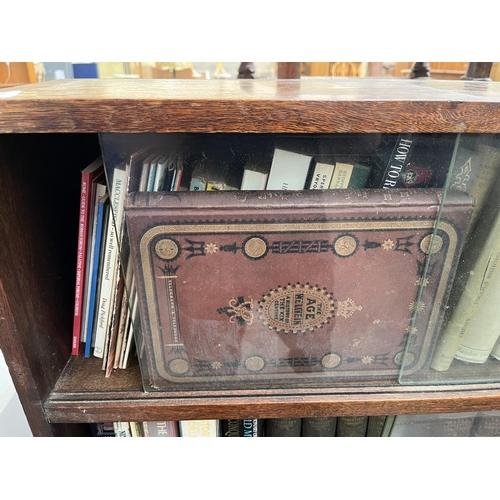 186 - A mid 20th century oak two tier bookcase with four glass sliding doors and books