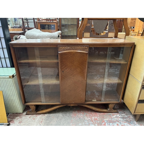 60 - An Art Deco style carved oak bookcase with central door and four glass sliding doors