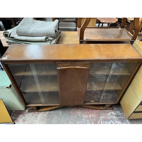 60 - An Art Deco style carved oak bookcase with central door and four glass sliding doors