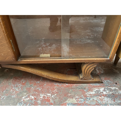 60 - An Art Deco style carved oak bookcase with central door and four glass sliding doors