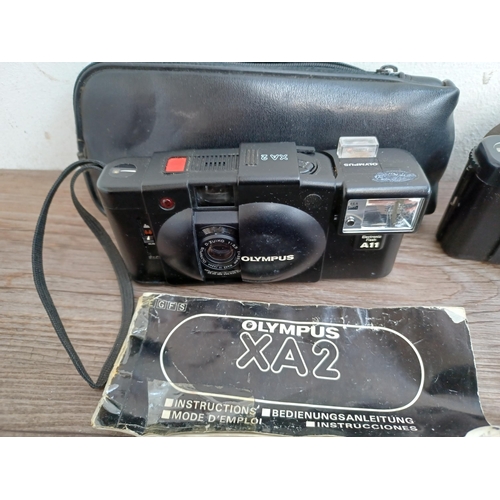 601 - Four Olympus compact clam-shell cameras, one cased XA2 fitted with A11 flash with instruction manual... 