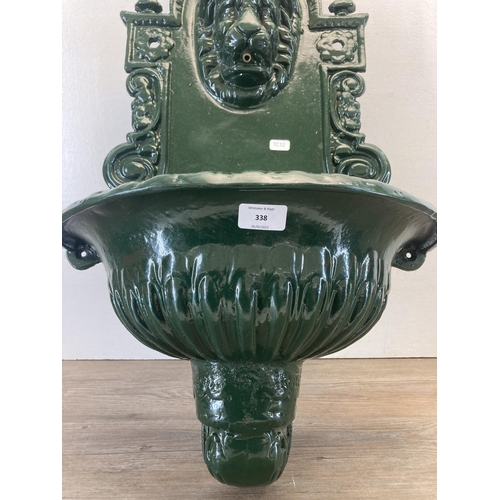 338 - A Victorian style green painted cast metal wall fountain with lion face design  - approx. 76cm high