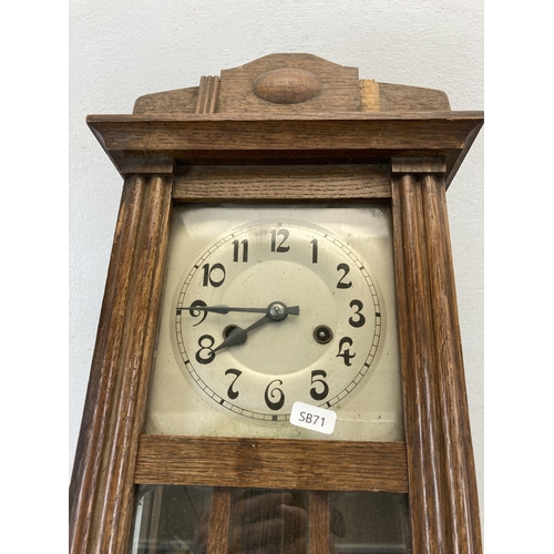 485 - An oak cased chiming wall clock with pendulum and key - approx. 60cm high