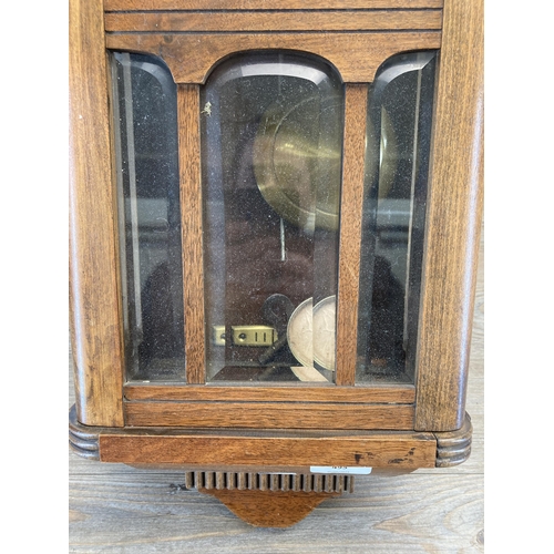 495 - An oak cased chiming wall clock with pendulum and key - approx. 61cm high