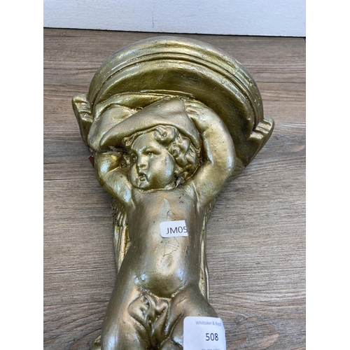 508 - A pair of gilded cast stone cherub wall brackets - approx. 30cm high