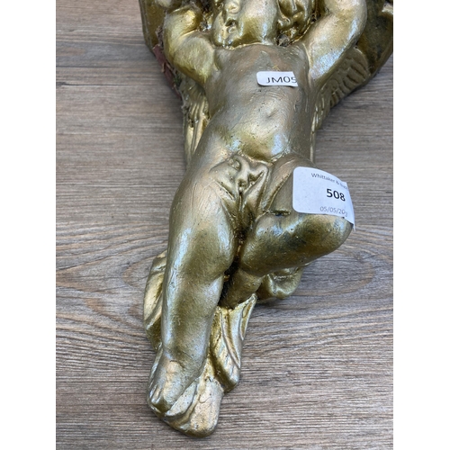 508 - A pair of gilded cast stone cherub wall brackets - approx. 30cm high