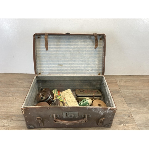 523 - A vintage brown leather suitcase containing fishing accessories to include three mahogany and brass ... 