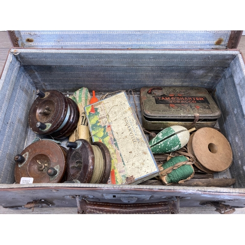 523 - A vintage brown leather suitcase containing fishing accessories to include three mahogany and brass ... 