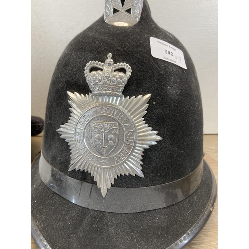 540 - Three police helmets and caps, two with Cheshire Constabulary badges