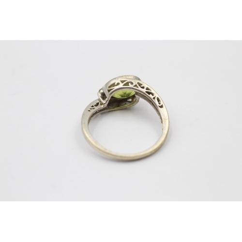 1139 - A 9ct white gold peridot and diamond bypass two stone ring, size M - approx. gross weight 2.3 grams