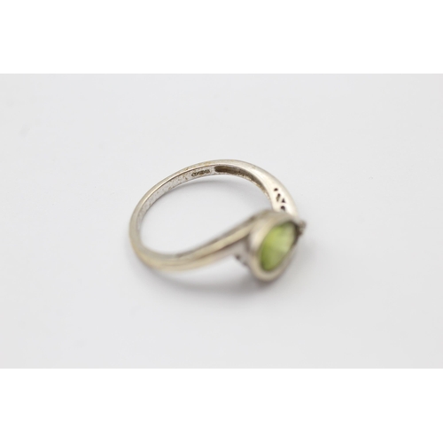 1139 - A 9ct white gold peridot and diamond bypass two stone ring, size M - approx. gross weight 2.3 grams