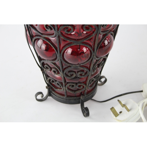 422 - A vintage cranberry glass table lamp with scrolled supports - approx. 45cm