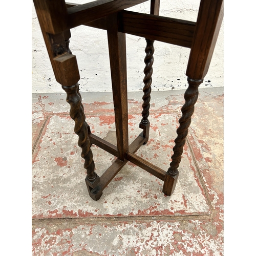 124 - An early/mid 20th century oak circular top folding occasional table on barley twist supports