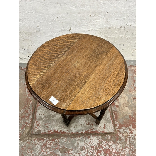 124 - An early/mid 20th century oak circular top folding occasional table on barley twist supports