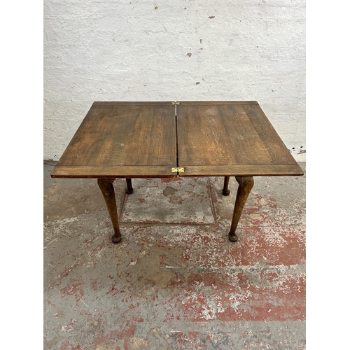 125 - A Georgian style oak fold over dining table with cabriole supports