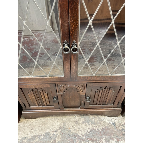 19 - An oak bookcase with two leaded glass doors and two linenfold cupboard doors