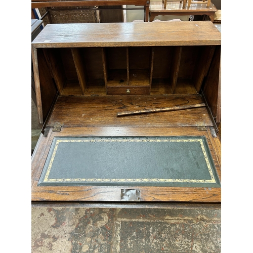 21 - A 1930s oak bureau with two drawers, fall front and baluster supports