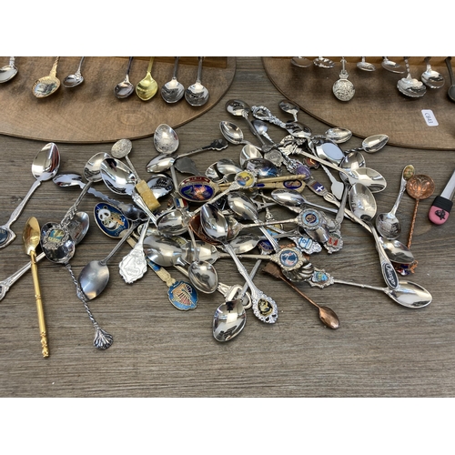 313 - A large collection of white metal collector's spoons and four hardwood wall mountable display plaque... 