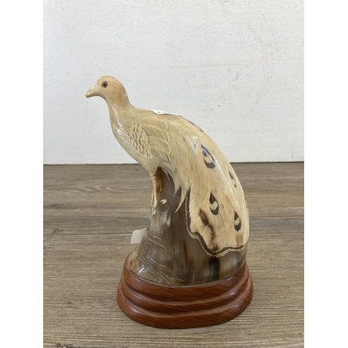 479 - A carved horn peacock figurine on oak plinth - approx. 20cm high