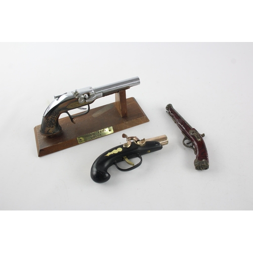 1409 - Three vintage novelty gun shaped cigarette/table lighters