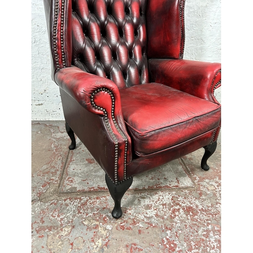 33 - An oxblood leather Chesterfield wingback armchair with cabriole supports