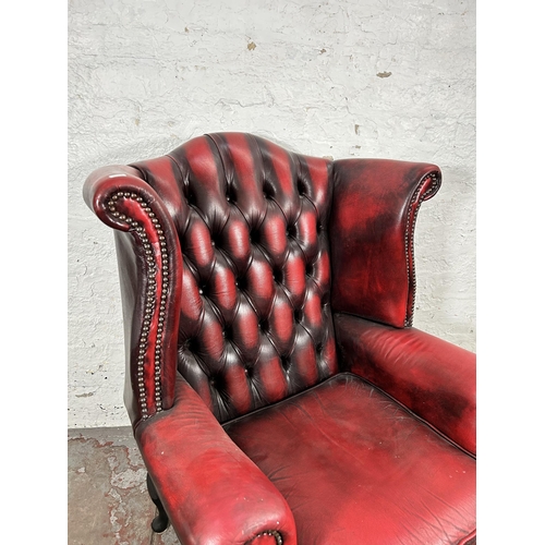 33 - An oxblood leather Chesterfield wingback armchair with cabriole supports