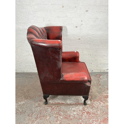 33 - An oxblood leather Chesterfield wingback armchair with cabriole supports