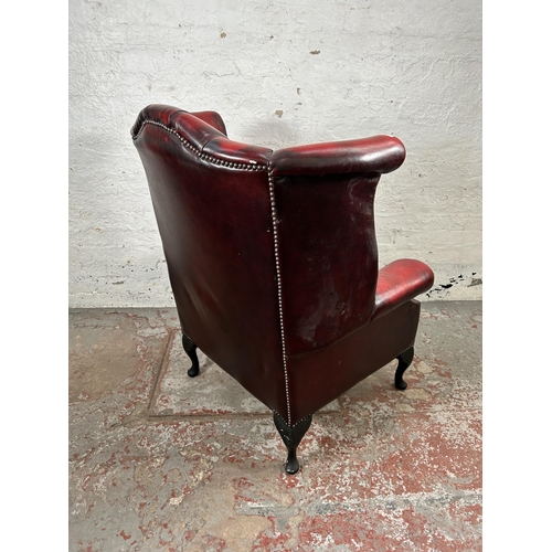 33 - An oxblood leather Chesterfield wingback armchair with cabriole supports