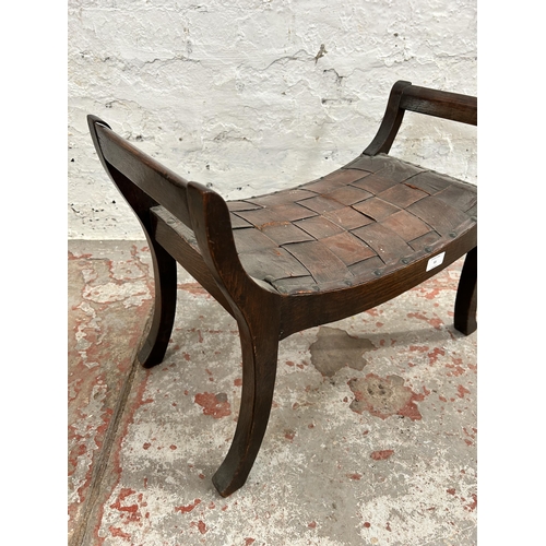 55 - An early 20th century oak and brown leather curved twin handled stool - approx. 43cm high x 60cm wid... 